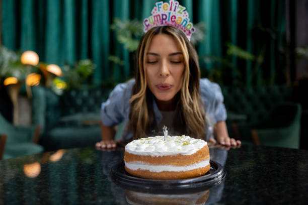 Happy woman celebrating her birthday and blowing out the candles on her cake